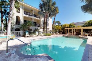 a swimming pool in front of a building with palm trees at La Casa Karen in Anna Maria