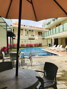 ポルト・デ・ガリーニャスにあるFlat Manawa A03のプールサイドのテーブル(椅子付)とパラソル付