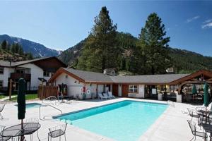 a swimming pool with chairs and a house and mountains at Aspen Suites 506: The Nest in Leavenworth