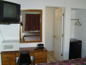 Habitación de hotel con TV y dormitorio en Cascade City Center Motel, en Lebanon