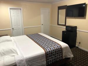 Whittier Travel Inn في ويتير: غرفة نوم بسرير وتلفزيون بشاشة مسطحة