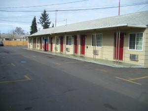 un edificio con puertas rojas en un aparcamiento en Cascade City Center Motel, en Lebanon