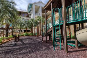 einen Spielplatz vor einem Gebäude mit Palmen in der Unterkunft Redfish Village M2-413 Blue Mountain Beach 30A (Condo) in Santa Rosa Beach