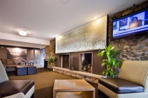 a living room with a fireplace and a tv on a stone wall at Best Western Plus Ottawa Kanata Hotel and Conference Centre in Ottawa