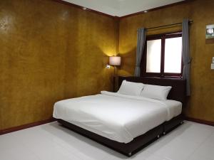 a bedroom with a white bed with a window at Superkids Resort in Phitsanulok