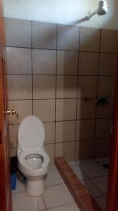 a bathroom with a toilet and a tiled wall at Ciudad de Las Rocas in La Fortuna Gallo Giro