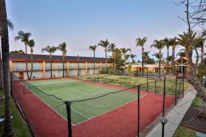 a tennis court in front of a building with palm trees at Mildura Inlander Resort in Mildura
