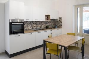 a kitchen with white cabinets and a wooden table at Villa Demarino in Castellana Grotte