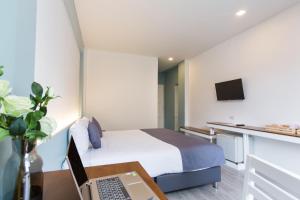 a hotel room with a bed and a laptop on a desk at At the Train Chiang Mai Hotel in Chiang Mai