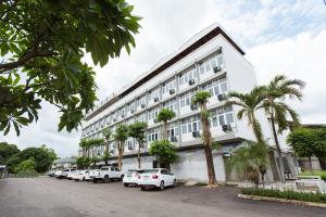 チェンマイにあるAt the Train Chiang Mai Hotelの前に車が駐車されている白い建物