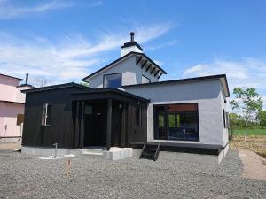 a small black and white house with a roof at Tsukushi Village in Tsurui