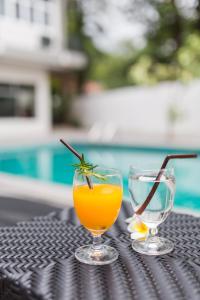 two glasses of orange juice on a table next to a pool at At the Train Chiang Mai Hotel in Chiang Mai