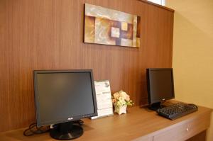 a desk with two computer monitors and a keyboard at Hotel Route-Inn Igaueno -Igaichinomiya Inter- in Iga