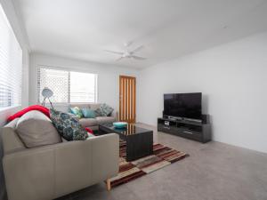 sala de estar con sofá y TV de pantalla plana en Beerburrum St 2 22 Dicky Beach en Caloundra