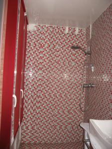 y baño con ducha y pared de azulejos rojos. en Chez Catie en Quintin