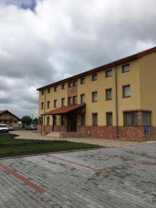 a large yellow building with a parking lot in front of it at Penzión Petrov grunt in Košúty