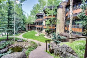 a building with a walkway next to a pond at Cozy Slopeside Condo in Snowmass Village