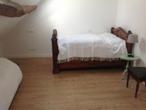 - une chambre avec un lit avec des draps blancs et une table dans l'établissement Au Pied des Vignes, à Santenay
