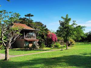 een huis met een groene tuin met bomen en gras bij Jasmine Hills Lodge in Doi Saket