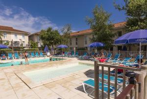 a pool at a hotel with chairs and umbrellas at Résidence Odalys Le Petit Pont in Hourtin