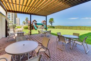 un patio con mesas y sillas y un parque infantil. en Ocean Vista #102 en South Padre Island