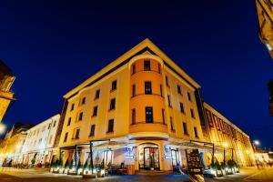 ein großes gelbes Gebäude mit einem Uhrturm darauf in der Unterkunft Old Town Hotel in Timişoara