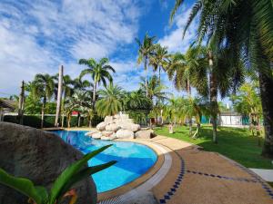a swimming pool in a yard with palm trees at Coconut Wells Phuket in Chalong