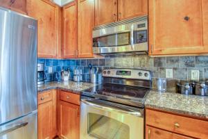 a kitchen with wooden cabinets and a stove and a microwave at The Cache in West Village in Copper Mountain