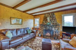 a living room with a leather couch and a stone fireplace at Longs Peak Cabin in Estes Park