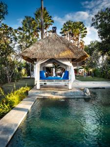 a gazebo with a bed and a swimming pool at Villa Cantik in Lovina