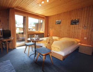Schlafzimmer mit einem Bett, einem Tisch und einem TV in der Unterkunft Pension Mezzaprada in Arosa