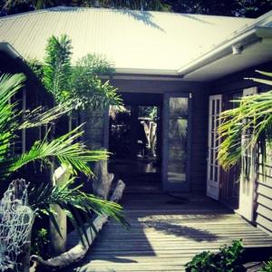 una veranda anteriore di una casa con palme di The Island Retreat a Kooringal