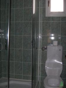 a bathroom with a toilet and a glass shower at Pensiunea Fenyő in Corund