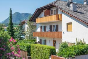 a white house with a balcony and bushes at Ferienwohnungen Reiterer in Appiano sulla Strada del Vino