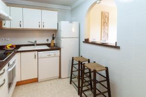 cocina con nevera blanca y 2 taburetes en Buganvilla, en Oliva