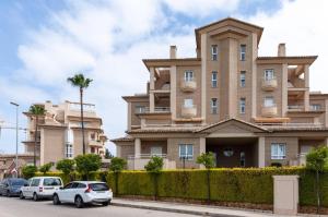 Un gran edificio con coches aparcados delante. en Buganvilla, en Oliva