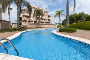 una piscina frente a un edificio con palmeras en Buganvilla, en Oliva