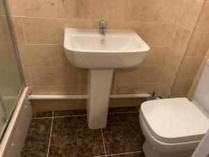 La salle de bains est pourvue d'un lavabo blanc et de toilettes. dans l'établissement Serviced Accommodations, à Luton