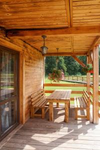 porche de madera con mesa de madera y 2 bancos en Uroczysko Trzyrzeczki, en Dąbrowa Grodzieńska-Wieś