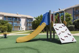 um parque infantil com escorrega num parque em Résidence Odalys Du Port em Hourtin
