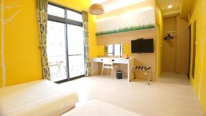 Habitación con paredes amarillas, cama y escritorio. en Hualien KeyInn Space, en Hualien City