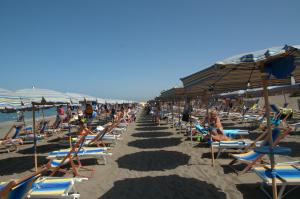 un montón de gente sentada en la playa en Residence Habitat, en Marina di Bibbona