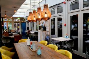 a restaurant with a wooden table and yellow chairs at Hotel Centraal in Someren