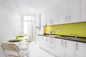 a kitchen with white cabinets and a table with chairs at Lisbon Zoo House II in Lisbon