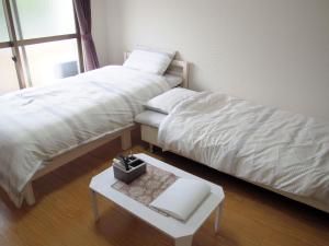 Un dormitorio con 2 camas y una mesa con un libro. en Free bike & free WIFI 301 Take it easy, en Kioto
