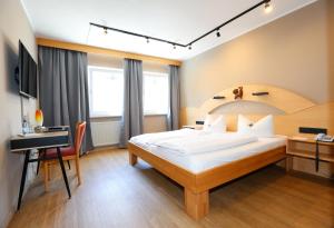 a bedroom with a large bed and a desk at Arthotel ANA Goggl in Landsberg am Lech