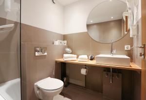 a bathroom with a toilet and a sink and a mirror at Arthotel ANA Goggl in Landsberg am Lech