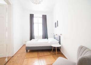 a white bedroom with a bed and a table at HeyMi Apartments Stadtpark in Vienna