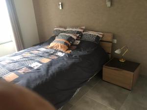 a bed with a black comforter and pillows on it at l’appartement du Plateau d’Hauteville in Hauteville-Lompnes