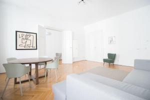biały salon ze stołem i krzesłami w obiekcie HeyMi Apartments Stadtpark w Wiedniu
